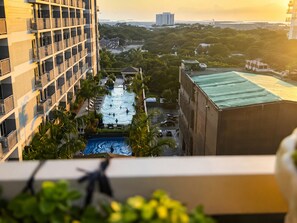 Un edificio de gran altura con piscina en la azotea, rodeado de palmeras y vistas de la ciudad.