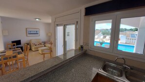 Et moderne køkken med granitbordplader, en indbygget vask og udsigt til en swimmingpool.