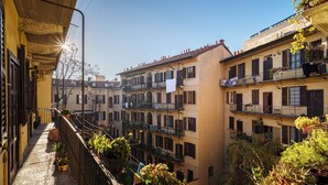 A narrow alleyway between buildings with balconies, potted plants, and hanging laundry. - Accomodo MIM21 Monolocale Porta Venezia (Milan)