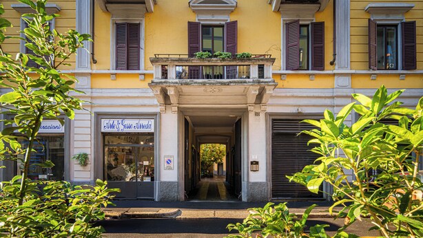A building with a yellow facade, multiple windows with shutters, and a central entrance with a balcony. - Accomodo MIM21 Monolocale Porta Venezia (Milan)