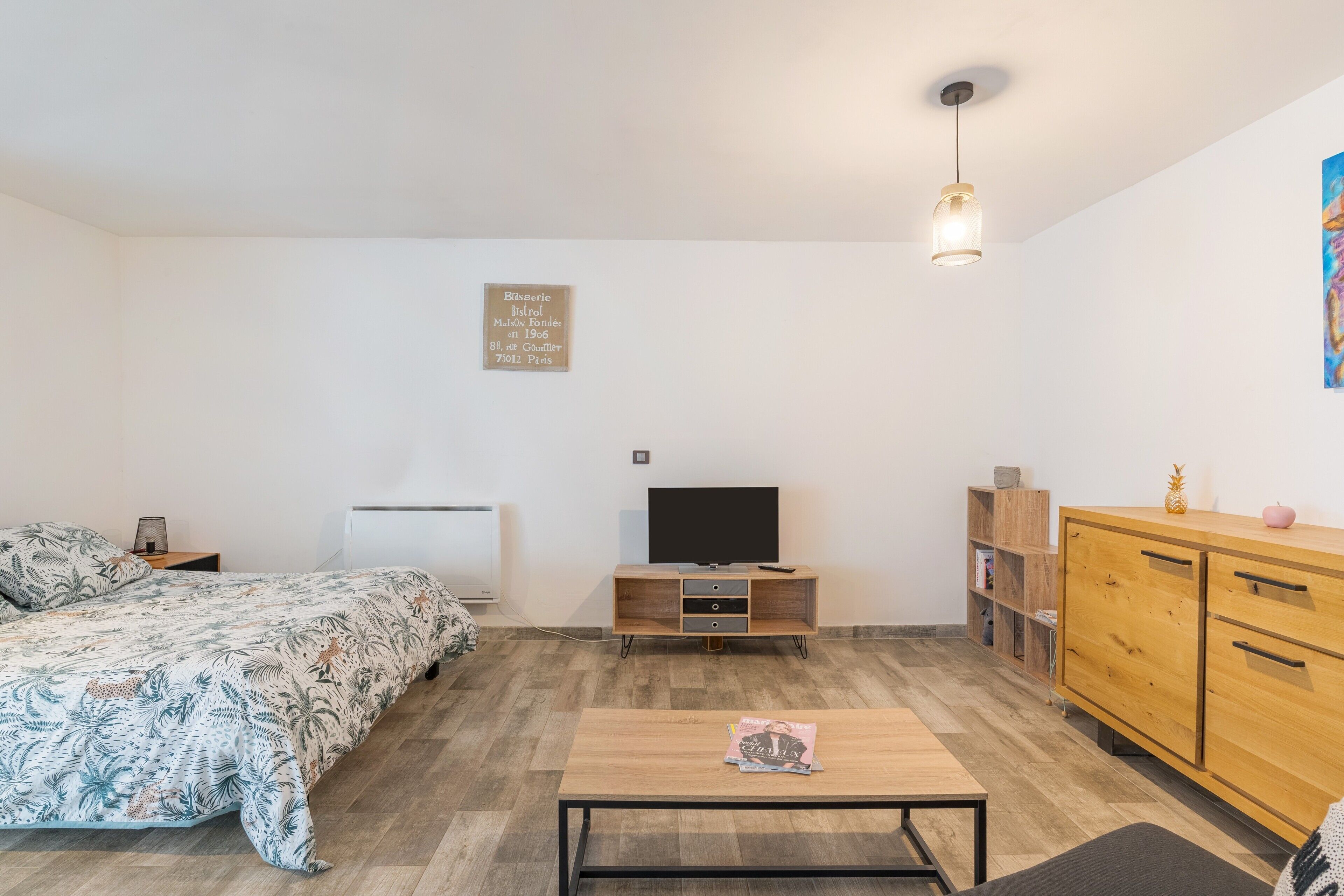 Une chambre à coucher avec un lit, une télévision, une armoire en bois et une petite table.