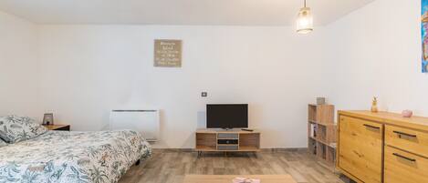 Une chambre à coucher avec un lit, une télévision, une armoire en bois et une petite table.