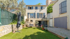 A courtyard with a lawn, outdoor furniture, a covered seating area, and a stone wall.