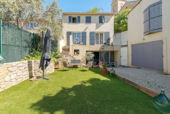 A courtyard with a lawn, outdoor furniture, a covered seating area, and a stone wall.
