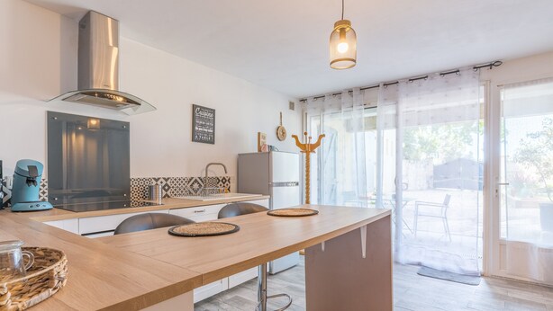 A modern kitchen with a central island, stainless steel range hood, and a pendant light.