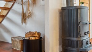 A wood-burning stove in a room with a sloped ceiling, a woven basket, and a stack of firewood. - "Naina" - 200m from the sea by Interhome (Grenaa)