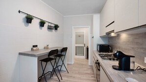 Una cocina compacta con barra americana, estufa a gas, microondas y un refrigerador pequeño.