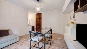 Una sala de estar moderna con una mesa de comedor de vidrio, un sofá y un televisor sobre un mueble.