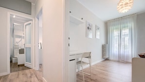 Un interior moderno con suelo de madera, un escritorio blanco, una silla y un radiador.