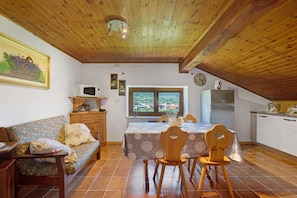 Une cuisine chaleureuse avec des poutres en bois, une table à manger avec des chaises, un canapé et une fenêtre donnant sur un beau paysage.