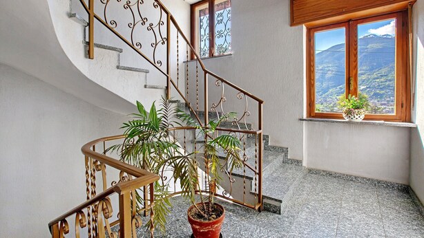 Eine Wendeltreppe mit schmiedeeisernen Geländern, einem Topfpflanzen und einem Fenster mit Bergblick.