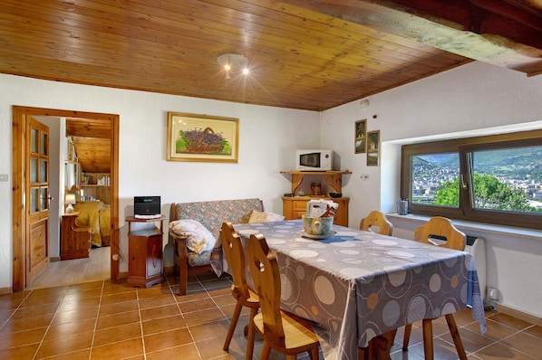 Une pièce comprenant une table à manger, des chaises, un lit, un téléviseur et une fenêtre donnant sur un paysage agréable.