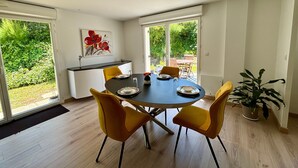 Uma área de refeições com uma mesa redonda, cadeiras amarelas e um vaso de planta.