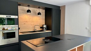 Uma cozinha moderna com forno embutido, cafeteira e iluminação pendente.