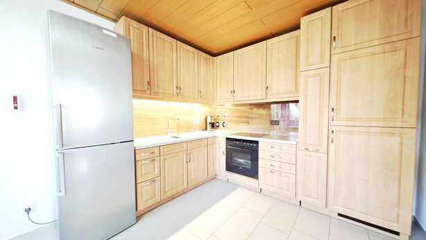 Eine moderne Küche mit Holzschränken, einem Edelstahlkühlschrank und einem Geschirrspüler.