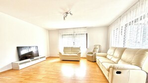 Ein großzügiges Wohnzimmer mit einem Flachbildfernseher, zwei Sofas und einem Deckenventilator.
