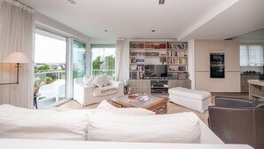 A modern living room with a sofa, coffee table, and a bookshelf. - Villa 'Mamina' with Sea View, Private Terrace and Wi-Fi (Larmor-Plage)