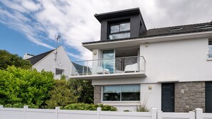 A modern two-story house with a balcony, large windows, and a stone facade. - Villa 'Mamina' with Sea View, Private Terrace and Wi-Fi (Larmor-Plage)