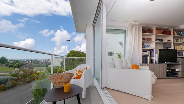 A modern living room with a balcony, a sofa, a TV, and a bookshelf. - Villa 'Mamina' with Sea View, Private Terrace and Wi-Fi (Larmor-Plage)