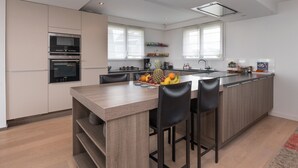 A modern kitchen with a central island, built-in appliances, and a large window. - Villa 'Mamina' with Sea View, Private Terrace and Wi-Fi (Larmor-Plage)