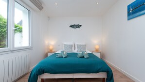 A bedroom with a bed, bedside lamps, a window, and a wall art piece. - Villa 'Mamina' with Sea View, Private Terrace and Wi-Fi (Larmor-Plage)