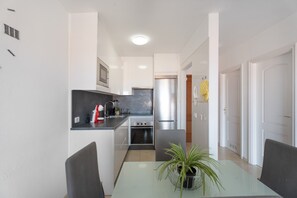 A modern kitchen with a dining area, including a table with chairs and a potted plant.