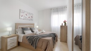 A bedroom with a bed, bedside tables, a nightstand, a mirror, and a painting on the wall. - Vacation 'Gabriela' with Shared Pool, Balcony and Wi-Fi (Candelaria)
