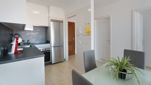 A modern kitchen with a built-in oven, a sink, and a dining area with a table and chairs. - Vacation 'Gabriela' with Shared Pool, Balcony and Wi-Fi (Candelaria)