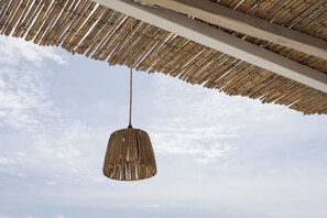 A hanging bamboo shade with a simple, modern pendant light fixture. - Porfyra Suite 1 (Agistri)