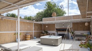 An outdoor patio with lounge chairs, a hot tub, and a hanging chair. - Porfyra Suite 1 (Agistri)