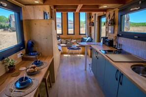 A compact kitchen with a dining area, large windows, and a view of the outdoors.
