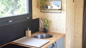 Una cocina moderna con encimera de madera, pileta de acero inoxidable, ventana y estante con plantas.