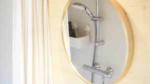 Un baño con tocador de madera, un espejo redondo, toallero y un estante pequeño con artículos de aseo.