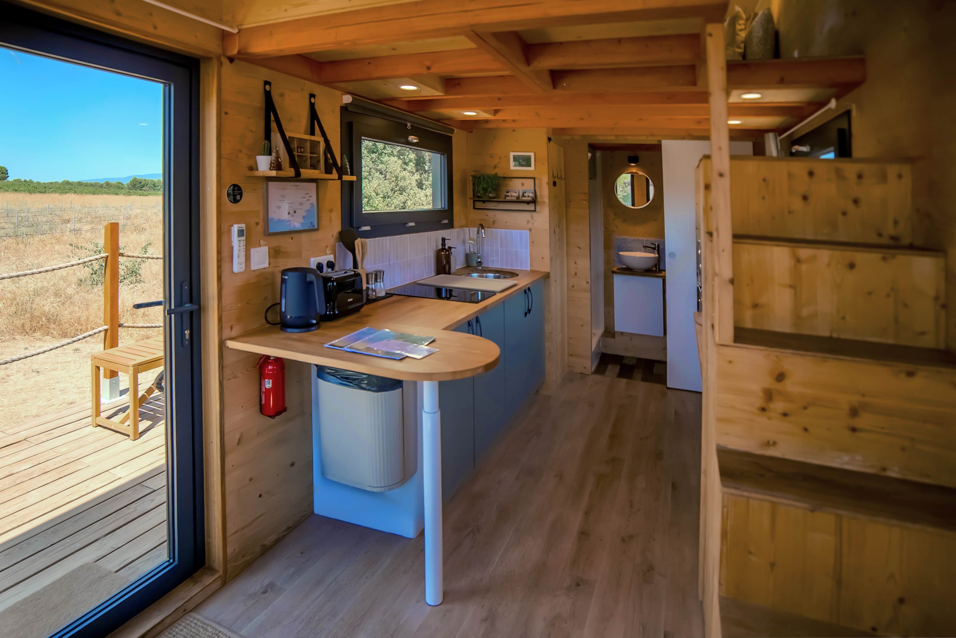 A compact kitchen with a built-in sink, a coffee maker, and a small trash bin.
