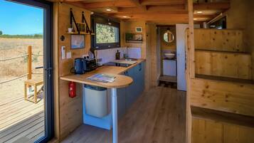 A compact kitchen with a built-in sink, a coffee maker, and a small trash bin.