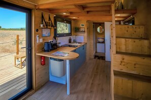 A compact kitchen with a built-in sink, a coffee maker, and a small trash bin.