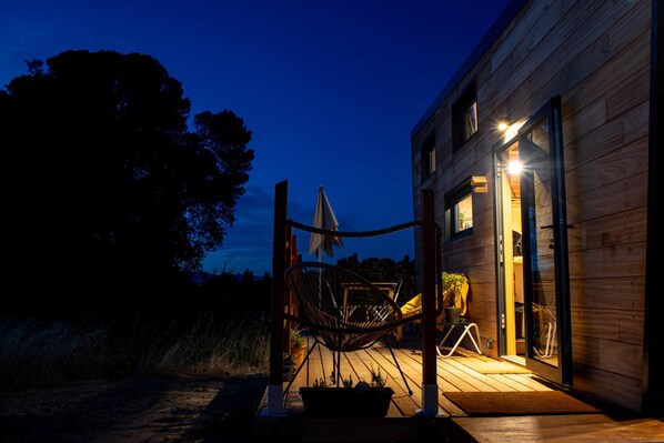 A wooden cabin with a porch, a hammock, and a potted plant.