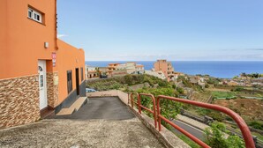 A coastal building with a staircase leading to a parking area, overlooking the sea.