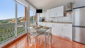 A modern kitchen with white cabinets, a stainless steel refrigerator, and a dining table with chairs.