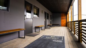 Un pasillo con bancos, suelo de madera y un felpudo con el logotipo de un hotel.