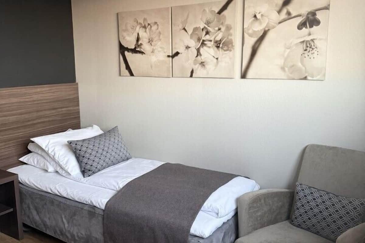 Ett hotellrum med en säng, en stol och ett konstverk som hänger på väggen.