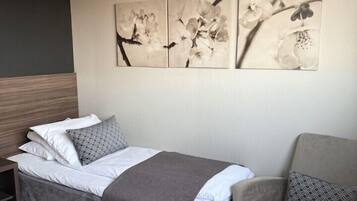 Quarto de hotel com uma cama, uma cadeira e uma obra de arte na parede.