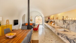 A modern kitchen with a marble countertop, a built-in stove, and a dining area with a wooden table and chairs. - Holiday Home 'Monte De Santiago' with Mountain View, Private Pool and Wi-Fi (São Domingos)