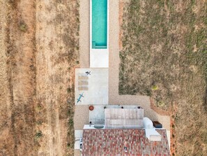 Vue aérienne d’une propriété dotée d’une piscine, d’un espace de détente extérieur abrité et d’une terrasse avec un toit à motifs.