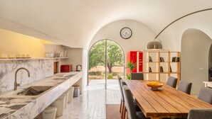 A modern kitchen with a marble countertop, a sink, and a dining area with a wooden table and chairs. - Holiday Home 'Monte De Santiago' with Mountain View, Private Pool and Wi-Fi (São Domingos)