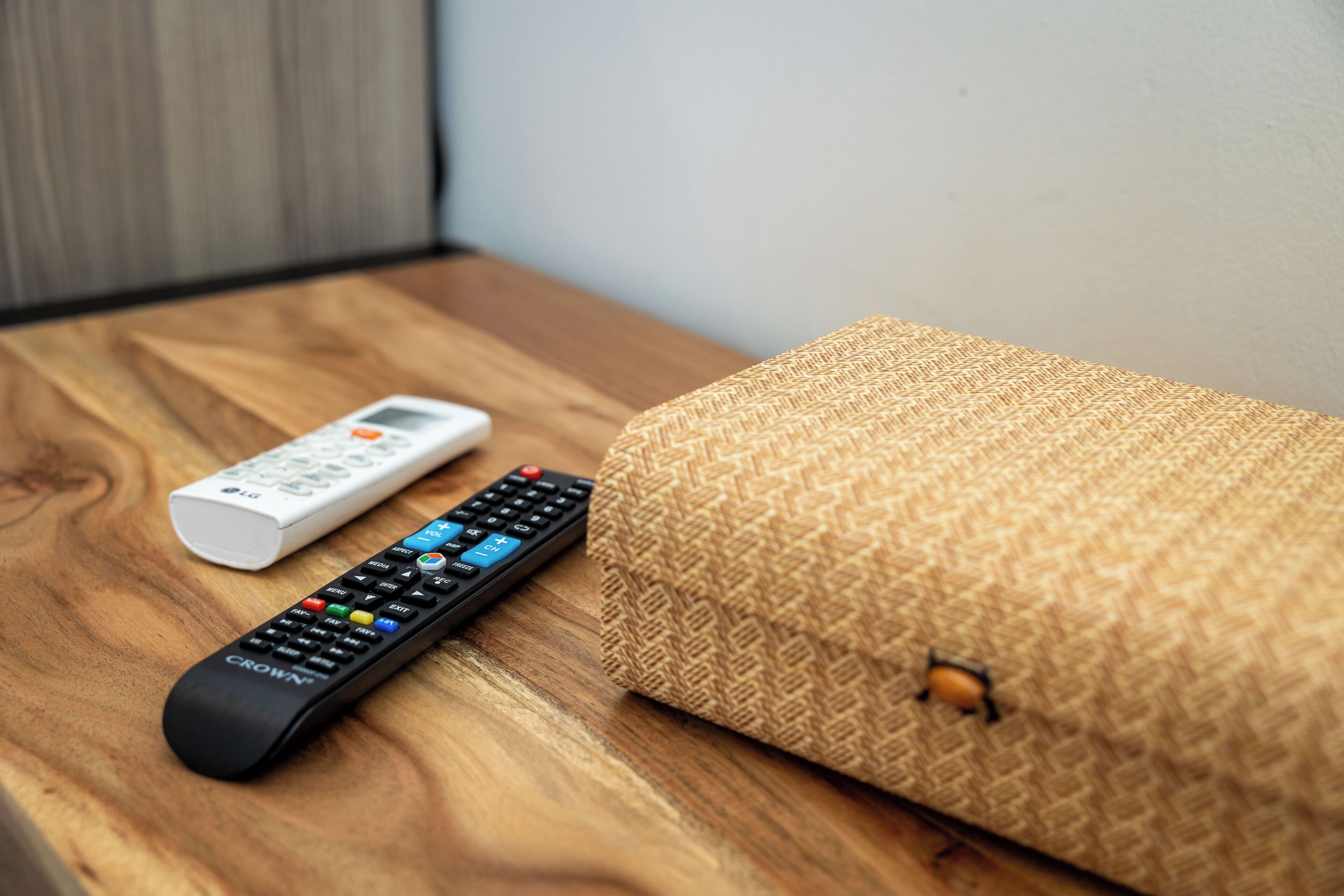 Un telecomando e una coperta arrotolata su un piano di legno.