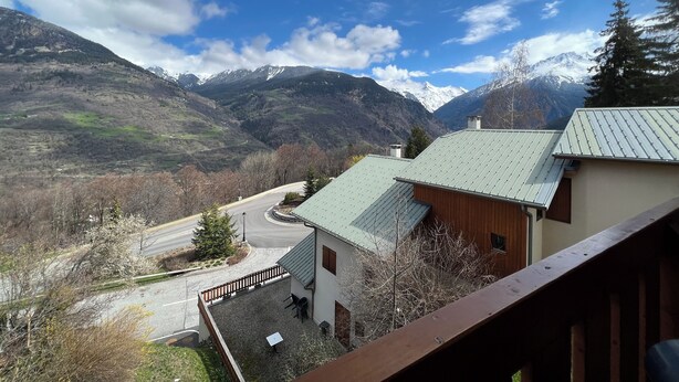 A mountain view from a building with a green roof, a paved driveway, and a wooden fence. - Apartment: Chez Pierre (Courchevel)