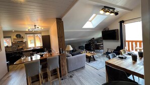 A spacious loft with a high ceiling, a kitchen area, a dining space, and a living area with a large window. - Apartment: Chez Pierre (Courchevel)