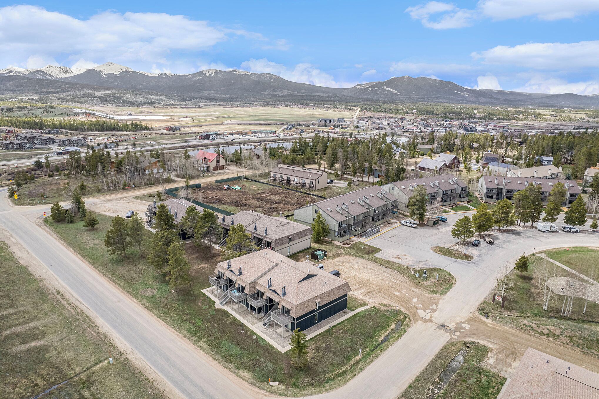 An aerial view of a commercial area with buildings, roads, and a mountainous backdrop.