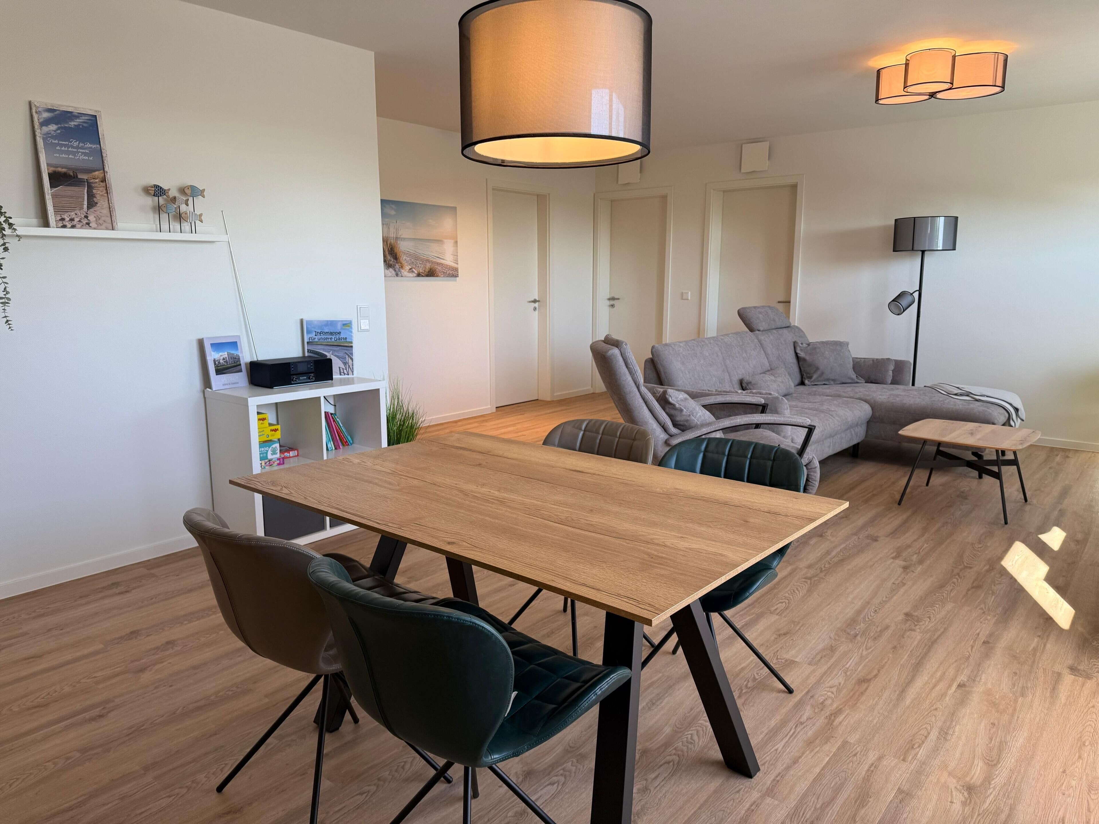 Een moderne woonkamer met een houten eettafel, twee stoelen, een grijze bank en een vloerlamp.